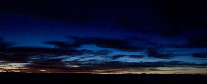 A panoramic night view of Haleakala Crater on Maui, showcasing the vast crater bathed in moonlight.