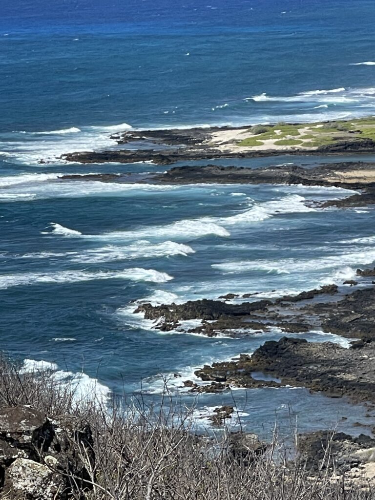 A powerful image of the Hawaiian shore with turquoise water churning and foaming due to strong winds. The dramatic scene showcases the wild beauty of the Hawaiian coast.