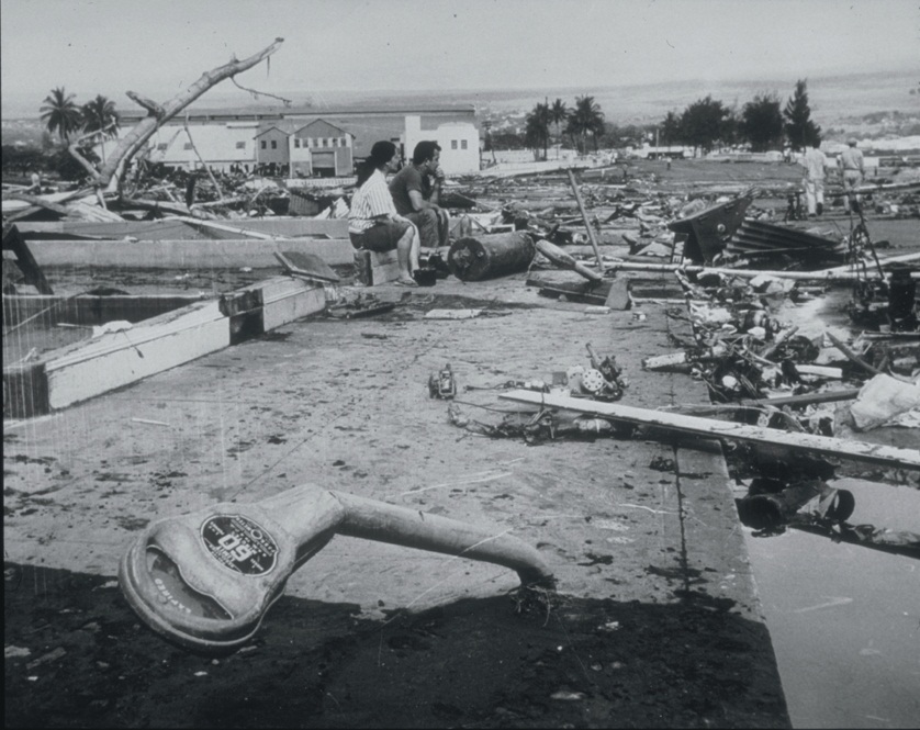 1960 Hilo tsunami destruction in Waiākea, Hawaii after Chile earthquake — bent parking meters, gutted concrete buildings, and debris-filled streets. 