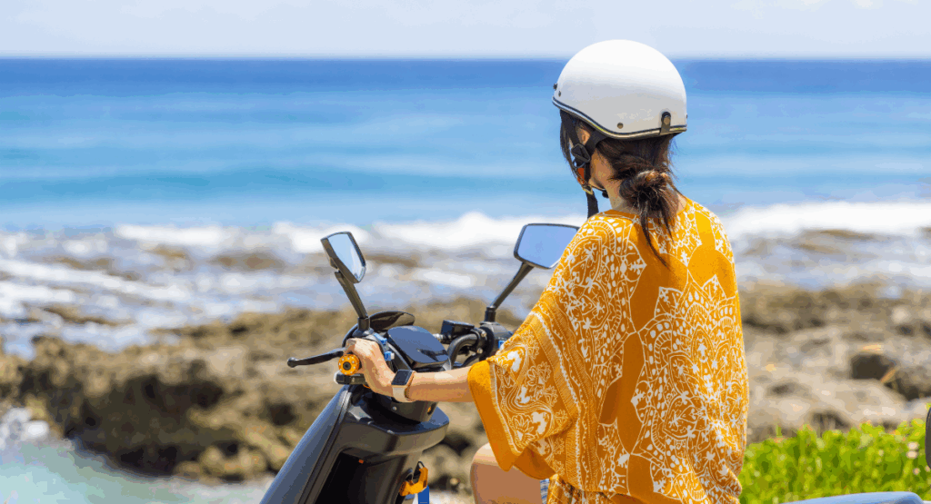 woman rider over looking ocean on her scooter